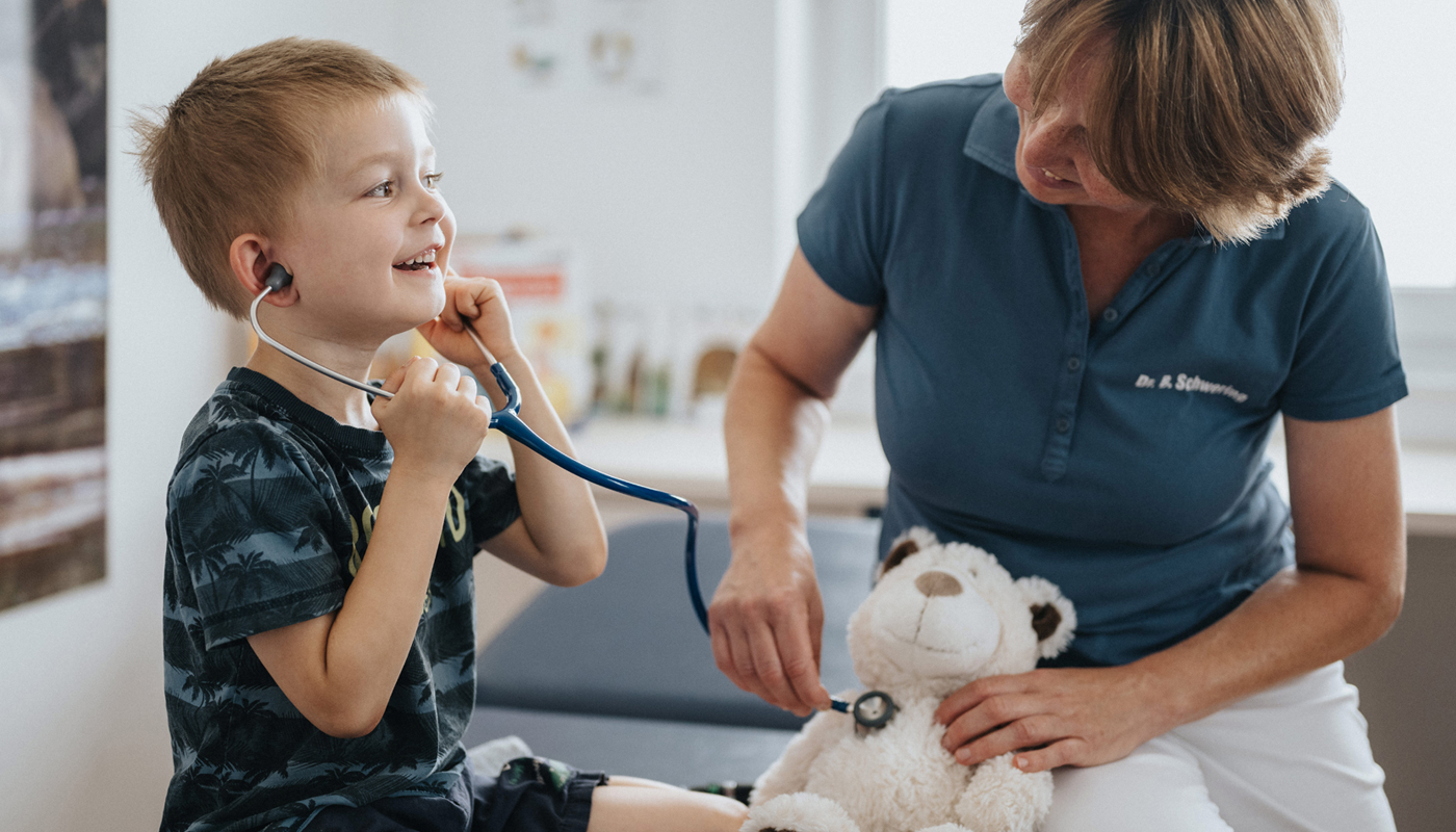 Kind hört mit Stethoskop einen Teddybären abp